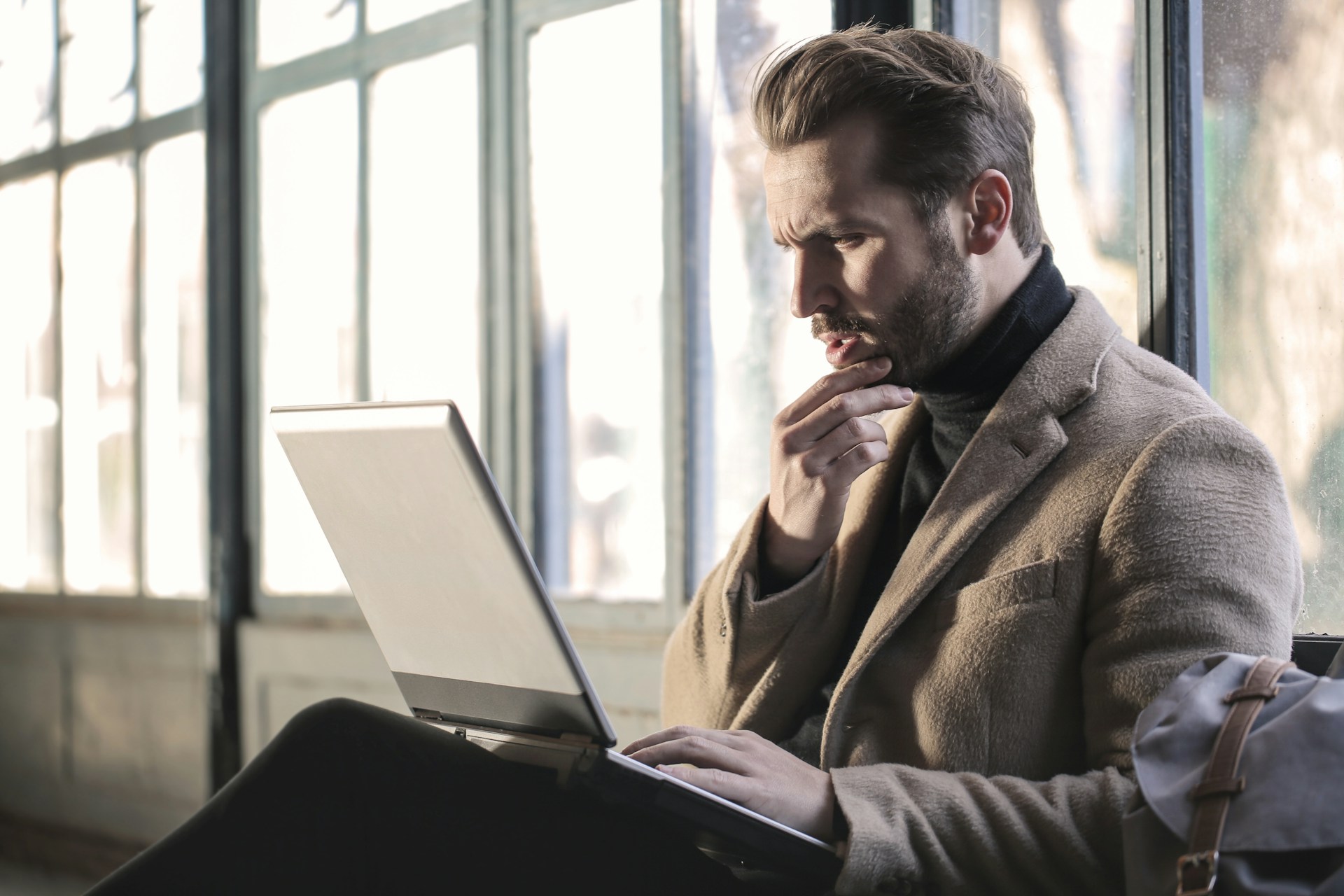 mężczyzna patrzący z zaciekawieniem na laptopa